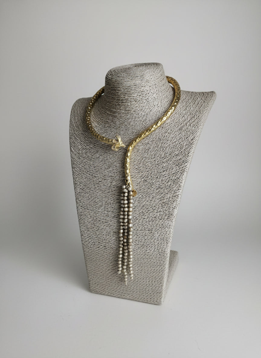 Collana etrusca regolabile in oro su bronzo con testa di ariete scolpita e fili di perle oro e topazio blu, design artigianale elegante e simbolico.