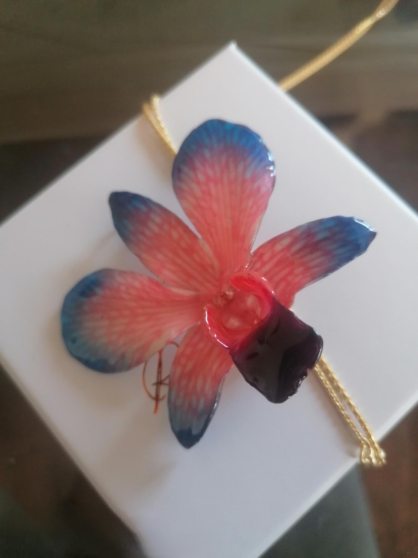 Collana con orchidea naturale azzurra e rossa inglobata in resina e saliscendi oro su bronzo regolabile
