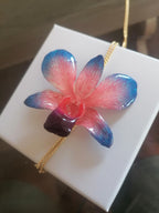 Collana con orchidea naturale azzurra e rossa inglobata in resina e saliscendi oro su bronzo regolabile