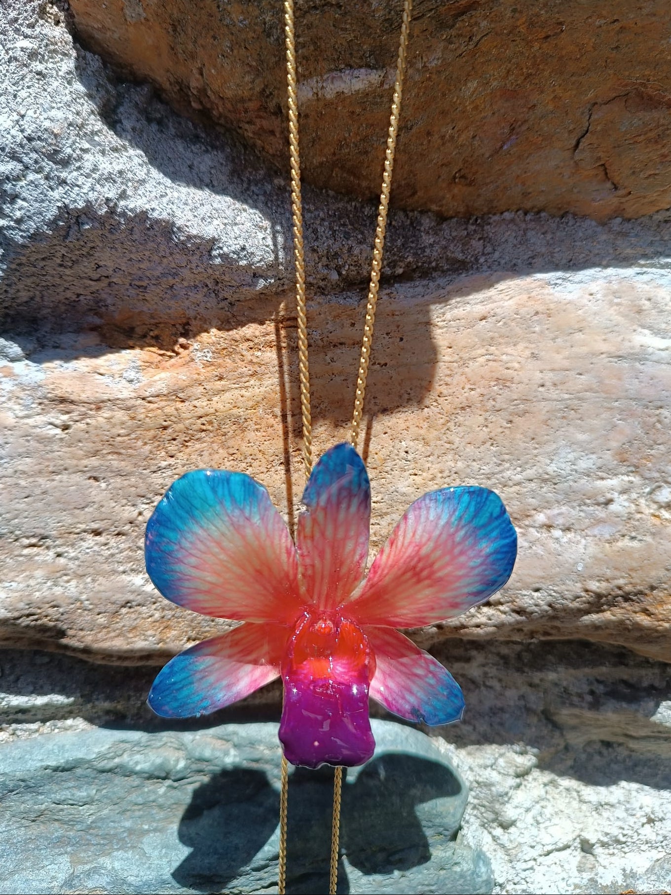 Collana con orchidea naturale azzurra e rossa inglobata in resina e saliscendi oro su bronzo regolabile