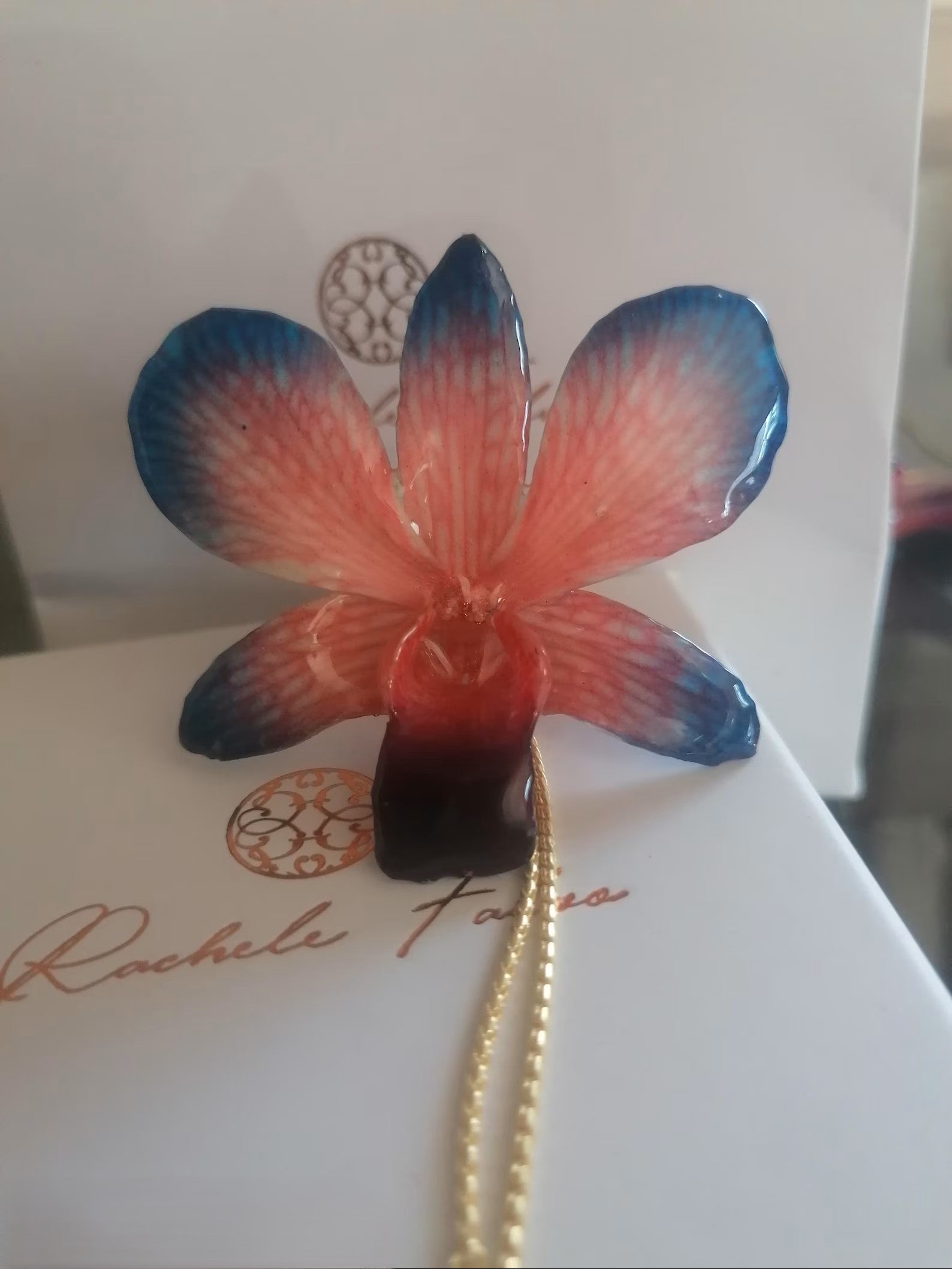 Collana con orchidea naturale azzurra e rossa inglobata in resina e saliscendi oro su bronzo regolabile