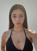 Collana dorata artigianale con ciondolo a melagrana in oro su bronzo e granatini rossi, simbolo di prosperità e abbondanza, dal design elegante e moderno.