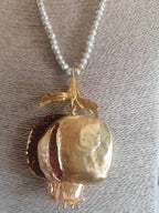 Collana artigianale ispirata al melograno con ciondolo in bronzo e granatini rossi, filo di perle bianche e dettagli borgogna e oro, design artistico e simbolico.