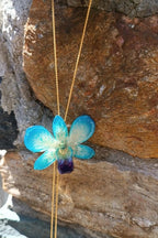 Collana con orchidea azzurra naturale inglobata in resina con saliscendi regolabile oro su bronzo