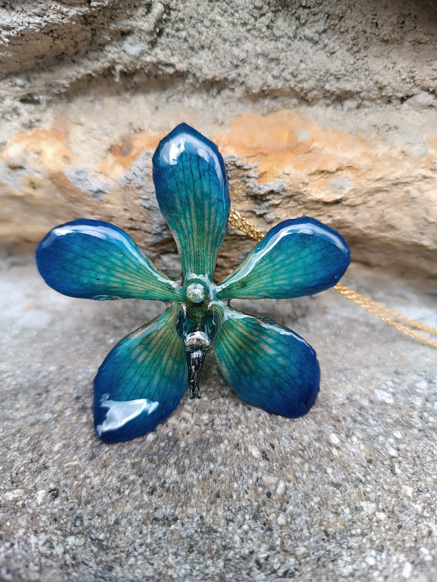 Collana con vera orchidea Mokara azzurra in resina e catenina in oro su bronzo.