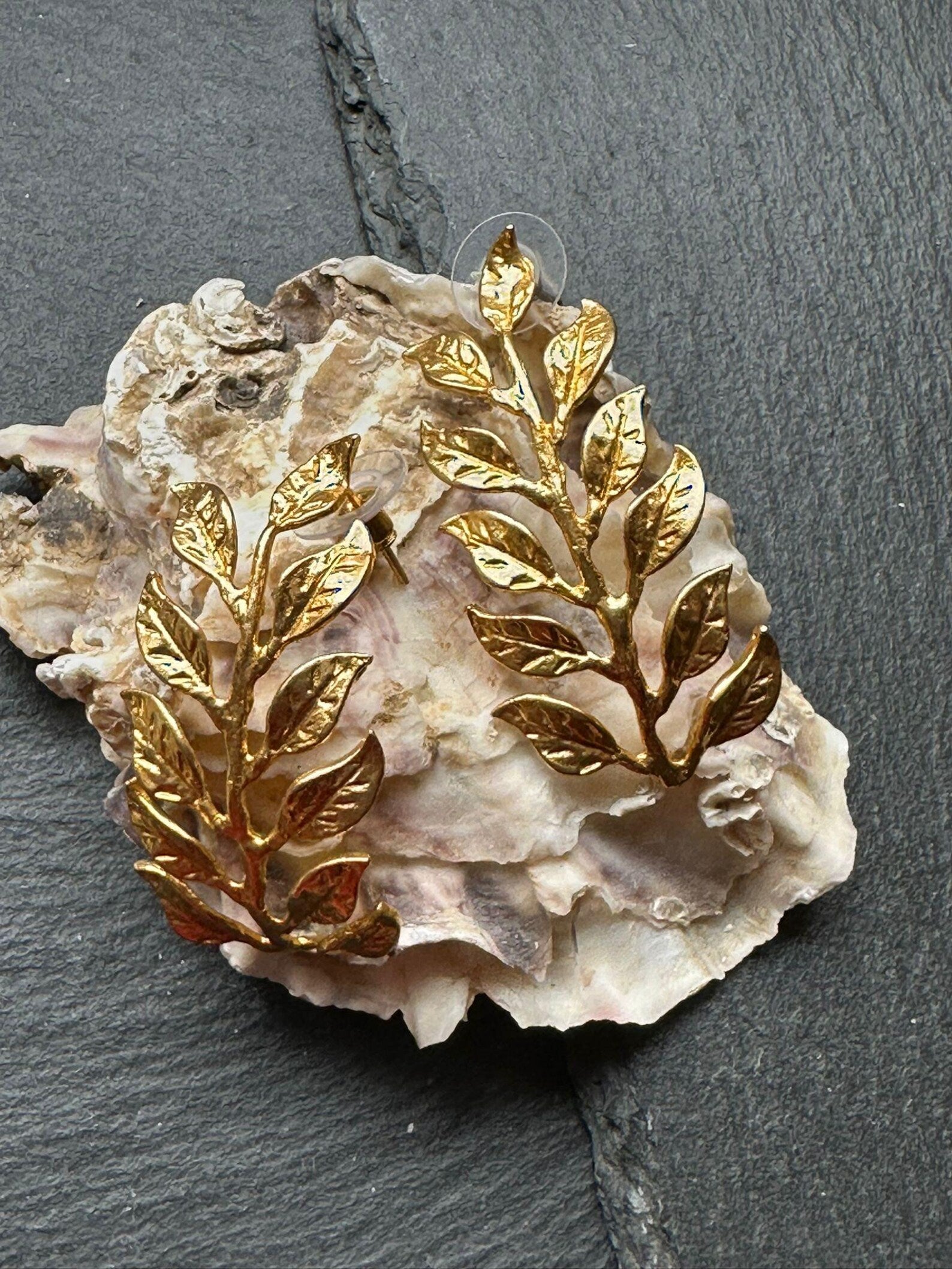 Orecchini dorati artigianali in oro su bronzo a forma di ramo fogliato con dettagli scolpiti, design elegante ispirato alla natura.