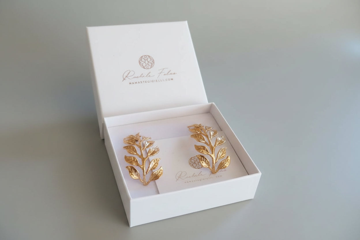 Orecchini dorati artigianali in oro su bronzo a forma di ramo fogliato con dettagli scolpiti, design elegante ispirato alla natura.
