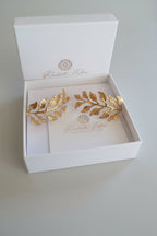 Orecchini dorati artigianali in oro su bronzo a forma di ramo fogliato con dettagli scolpiti, design elegante ispirato alla natura.