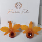 orecchini artigianali al lobo realizzati con intere orchidee vere in resina lucida, una variante  giallo ocra con sfumature viola, disposte sulla loro scatola regalo bianca firmata Rachele Falvo.