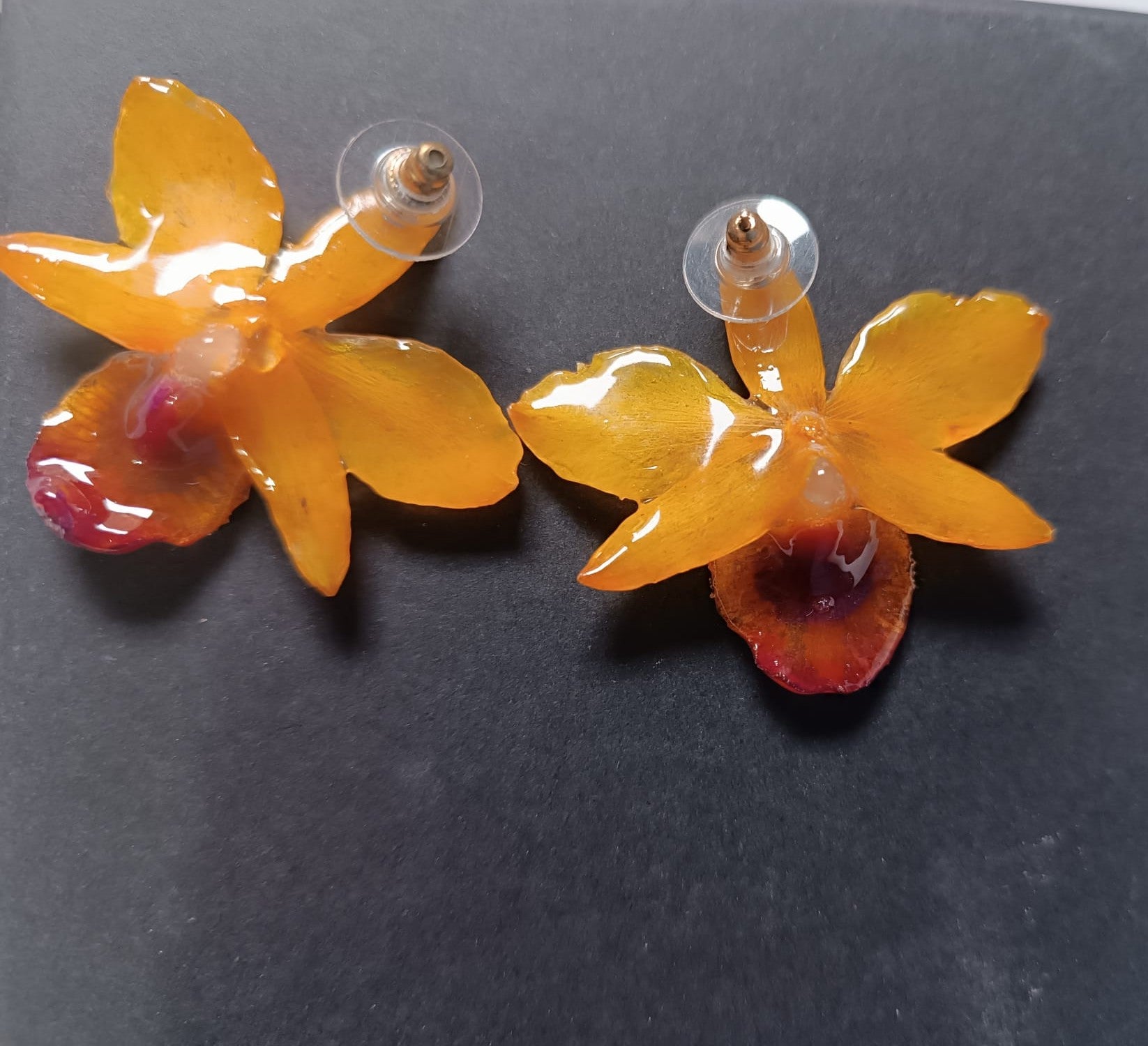 lato posteriore orecchini artigianali al lobo realizzati con intere orchidee vere in resina lucida, una variante  giallo ocra con sfumature viola