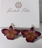 orecchini artigianali al lobo realizzati con intere orchidee vere in resina lucida, una variante  viola, disposte sulla loro scatola regalo bianca firmata Rachele Falvo.