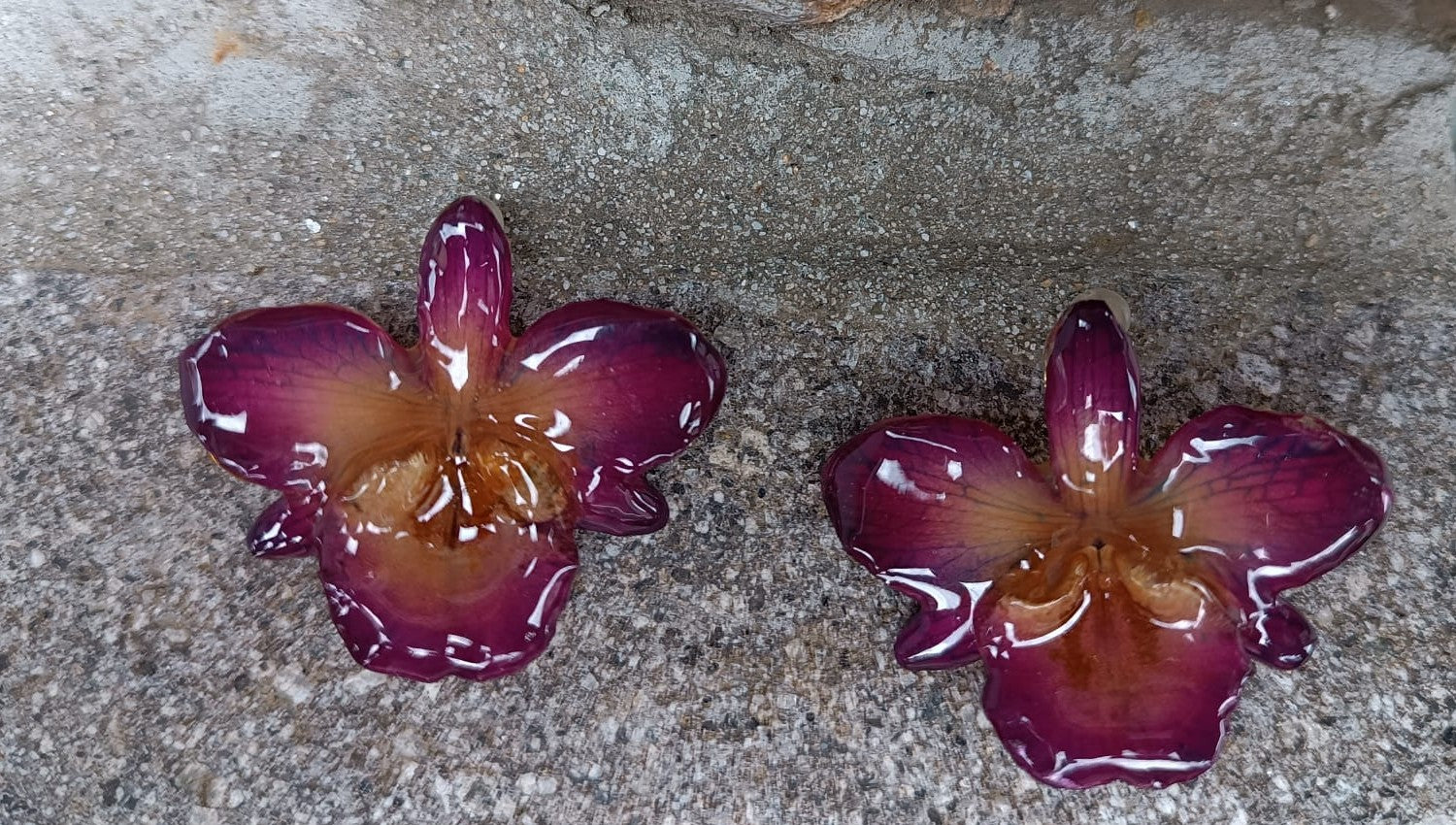 orecchini artigianali al lobo realizzati con intere orchidee vere in resina lucida, una variante viola, disposte sulla loro scatola regalo bianca firmata Rachele Falvo.