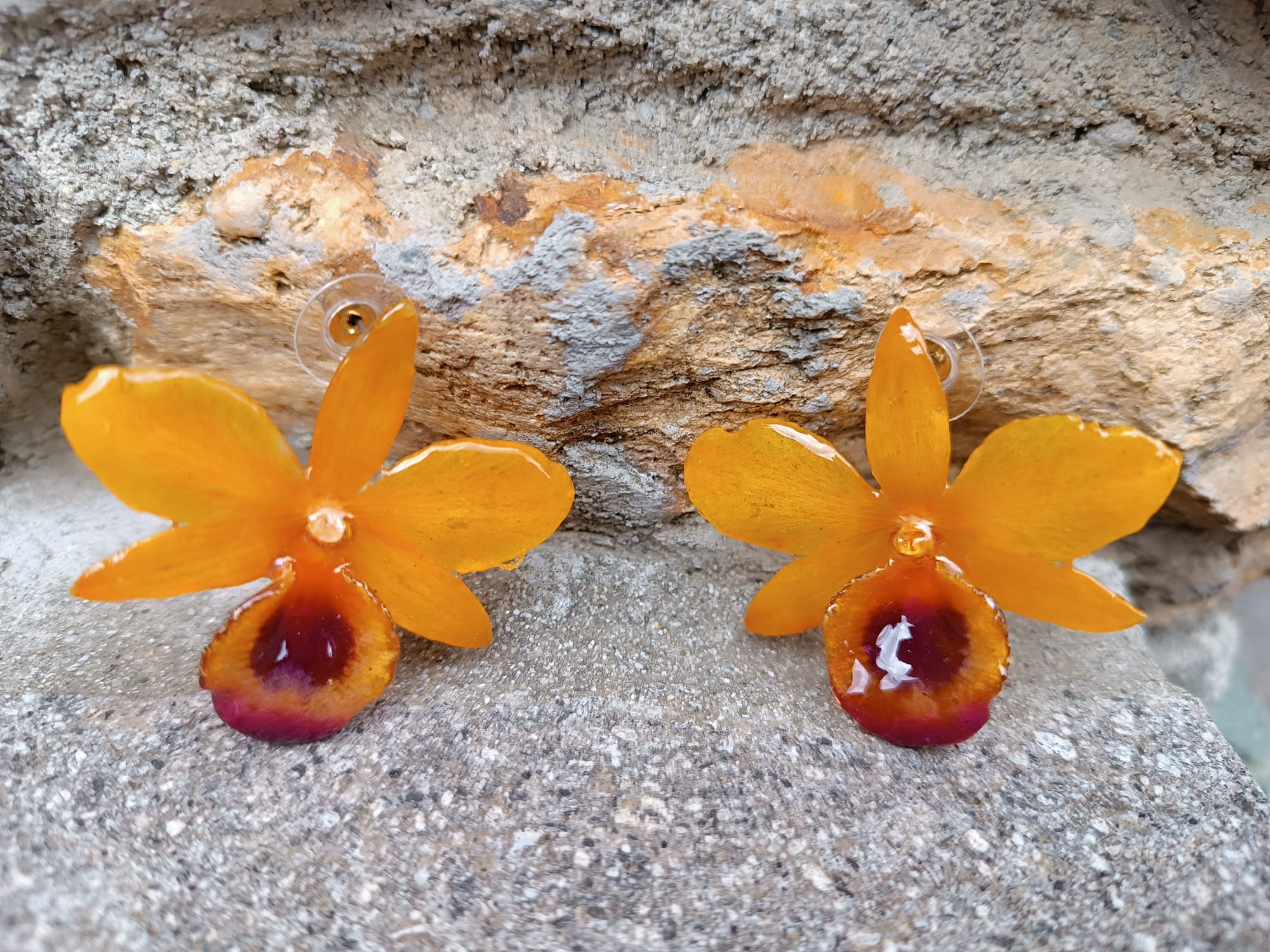 orecchini artigianali al lobo realizzati con intere orchidee vere in resina lucida, una variante  giallo ocra con sfumature viola