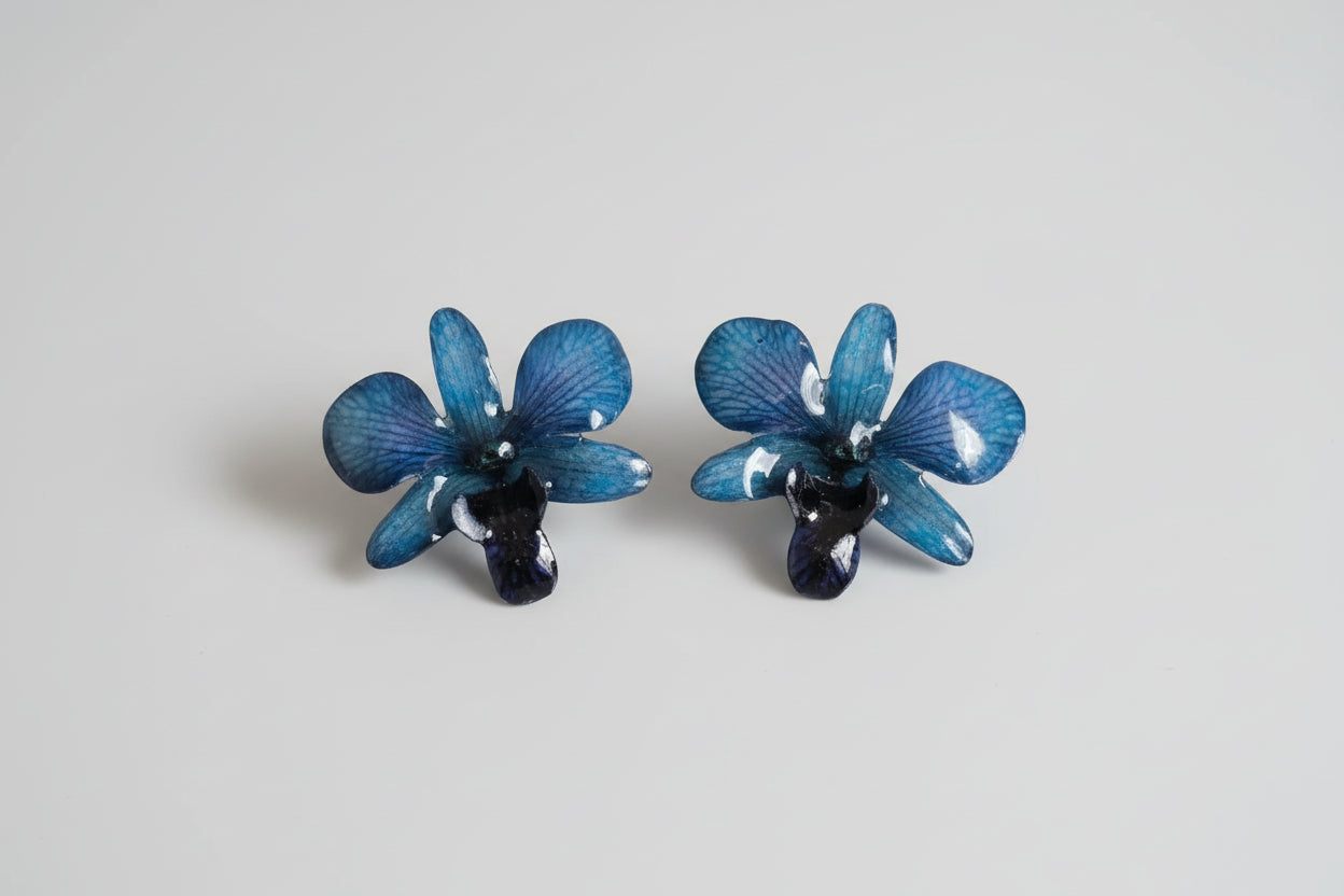 Orecchini con orchidee rare viola nere e blu inglobate in resina con venature lilla e tortora