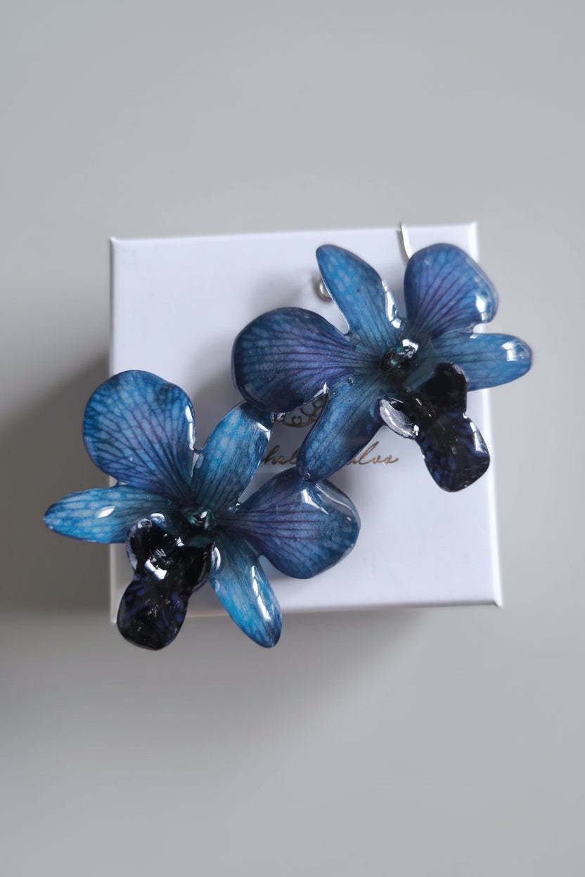 Orecchini con orchidee rare viola nere e blu inglobate in resina con venature lilla e tortora