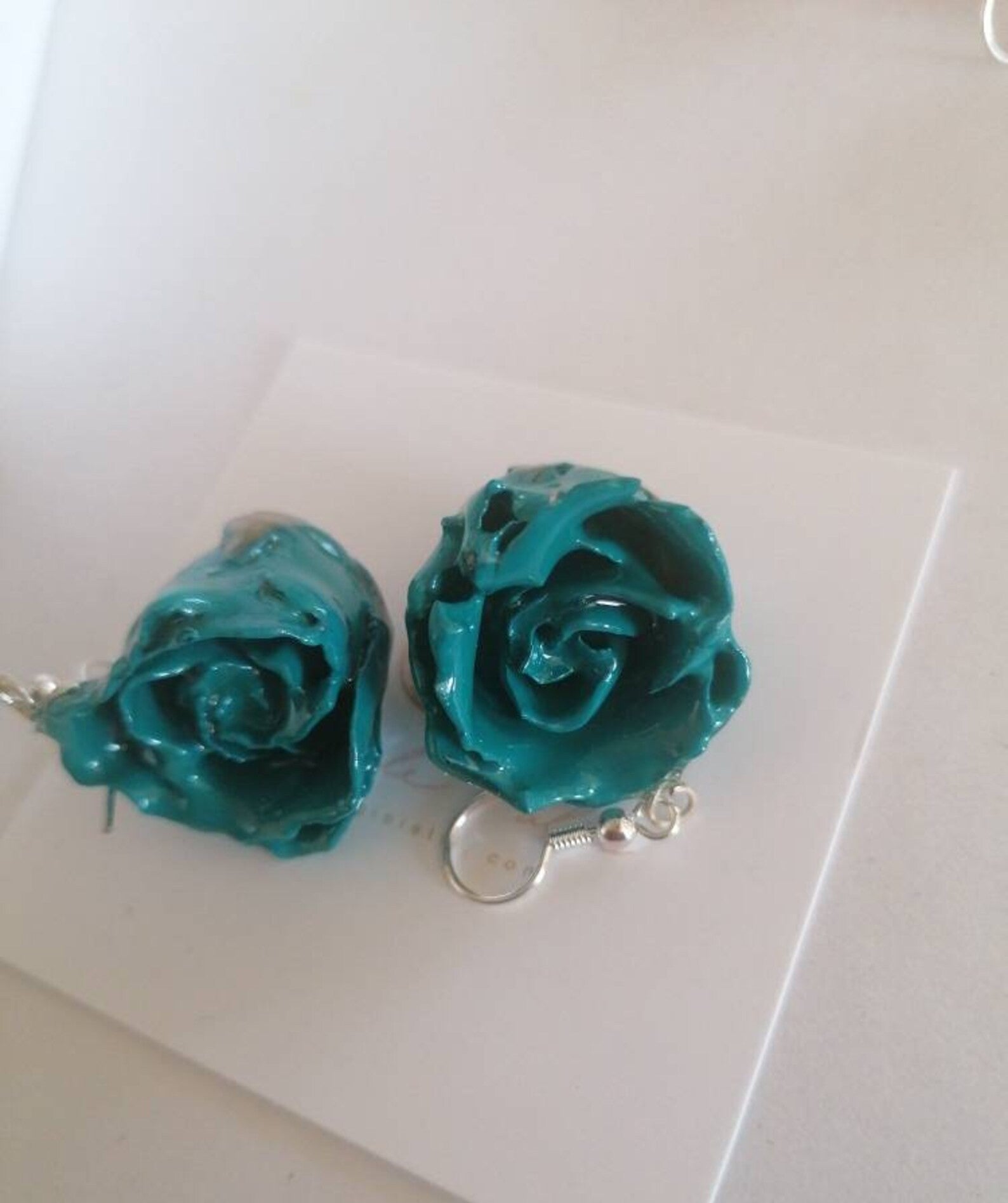 recchini pendenti artigianali Rachele Falvo realizzati con veri boccioli di rosa 3D in resina lucida e ganci d'argento, mostrati nei colori rosa antico, bianco, verde petrolio, arancio e fucsia