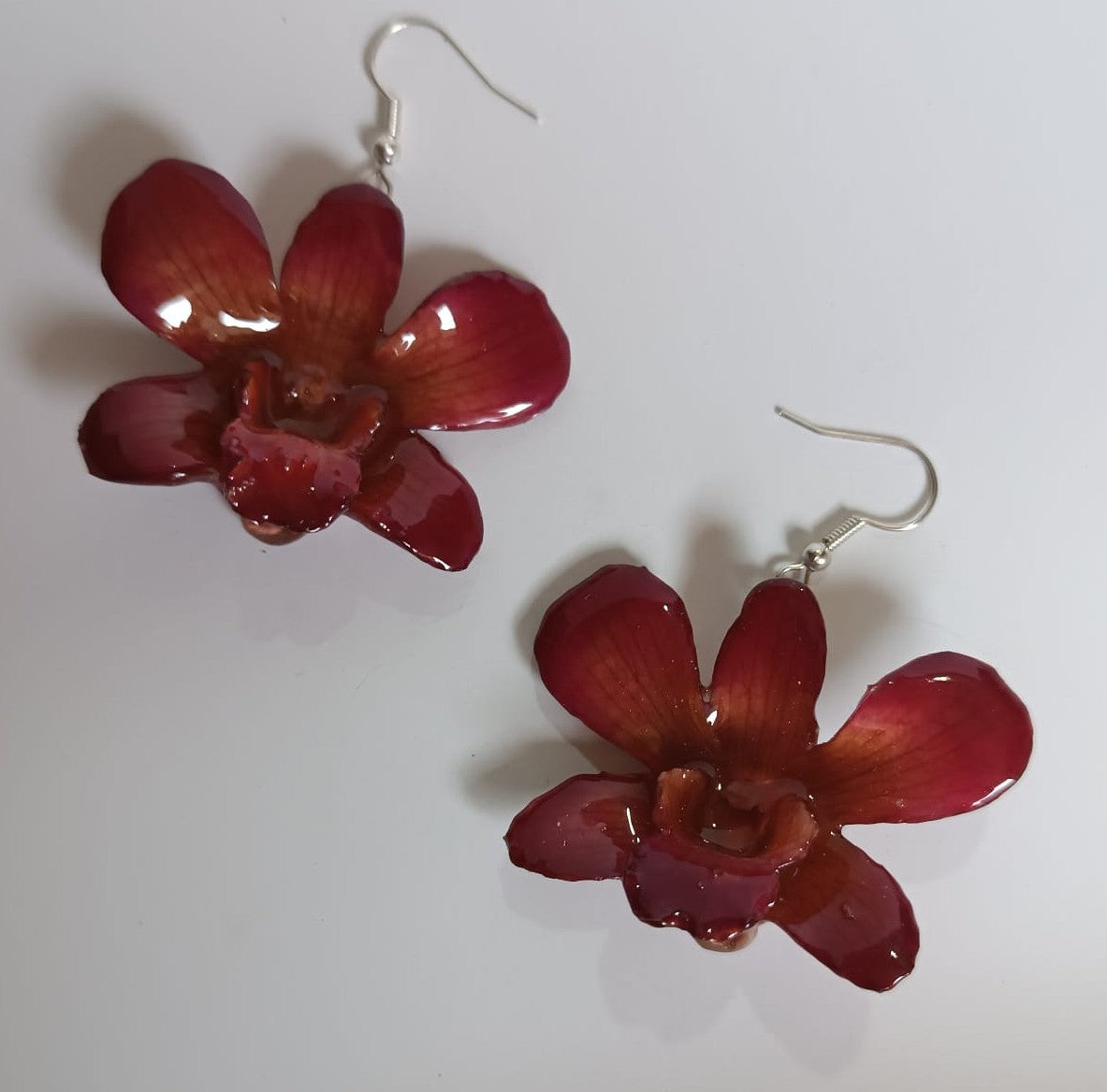 orecchini artigianali Rachele Falvo con un'intera orchidea vera rossa in resina lucida e gancio in argento
