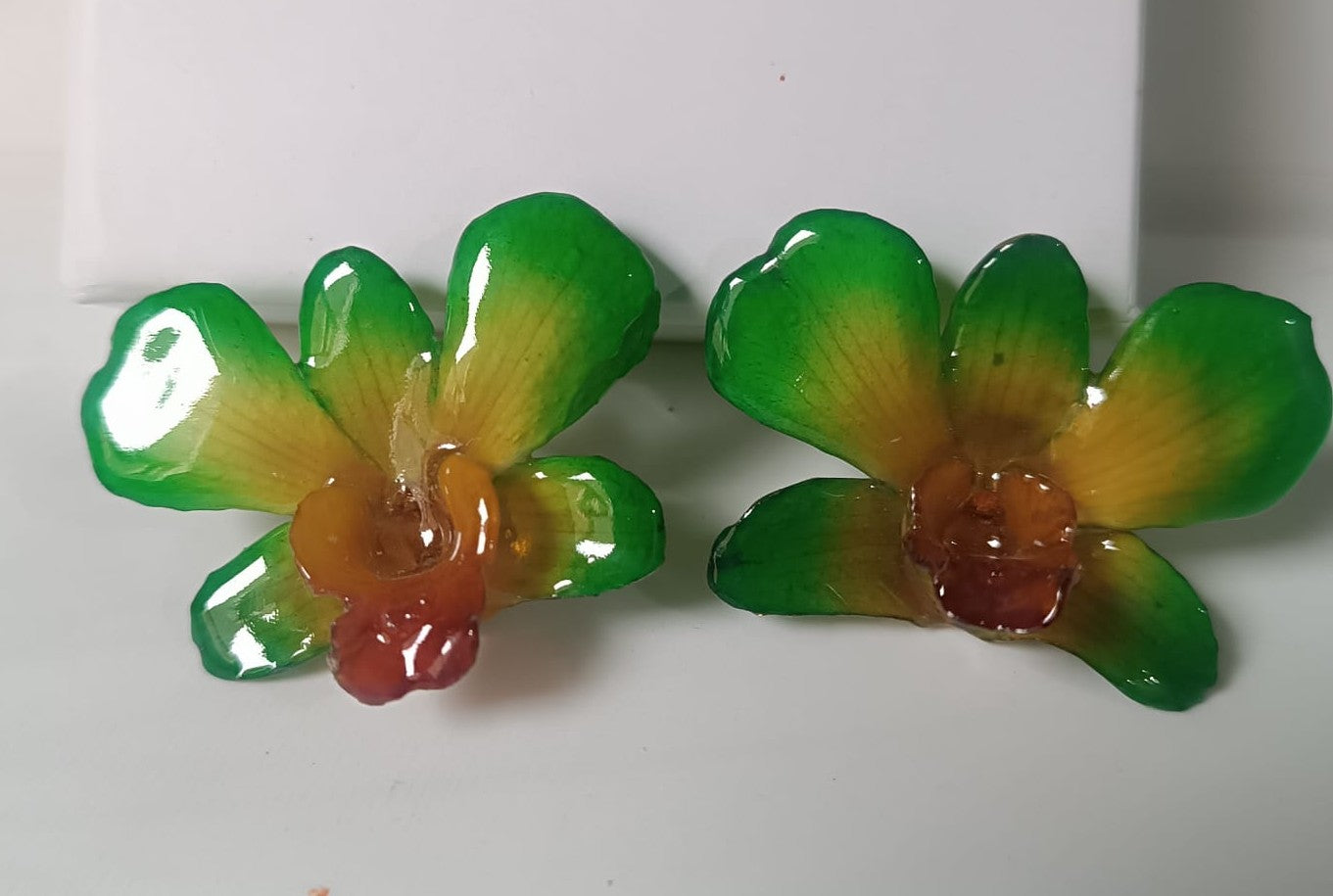orecchini pendenti artigianali Rachele Falvo, realizzati con intere orchidee vere sfumate in verde brillante, giallo ocra e centro fucsia viola in resina lucida.