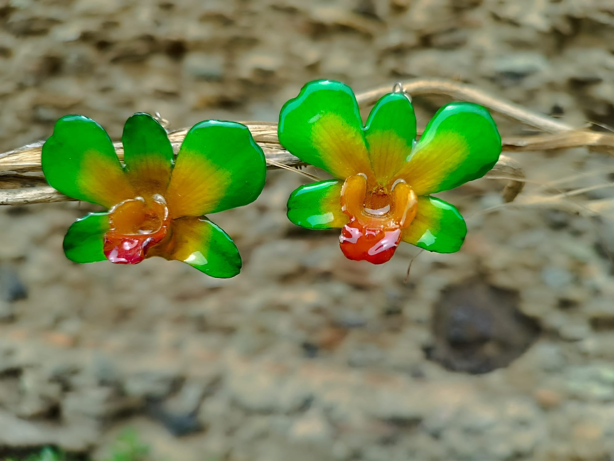orecchini pendenti artigianali Rachele Falvo, realizzati con intere orchidee vere sfumate in verde brillante, giallo ocra e centro fucsia viola in resina lucida.
