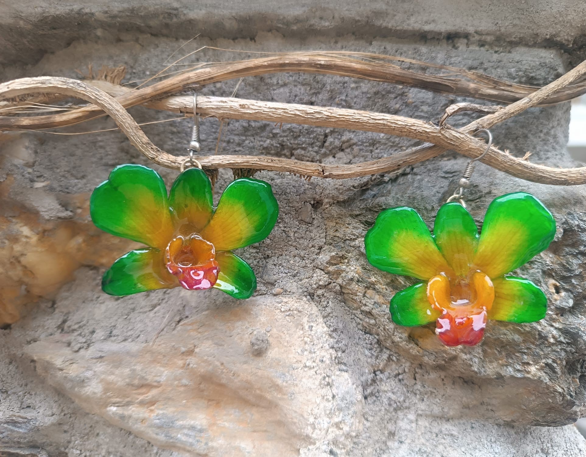 orecchini pendenti artigianali Rachele Falvo, realizzati con intere orchidee vere sfumate in verde brillante, giallo ocra e centro fucsia viola in resina lucida.