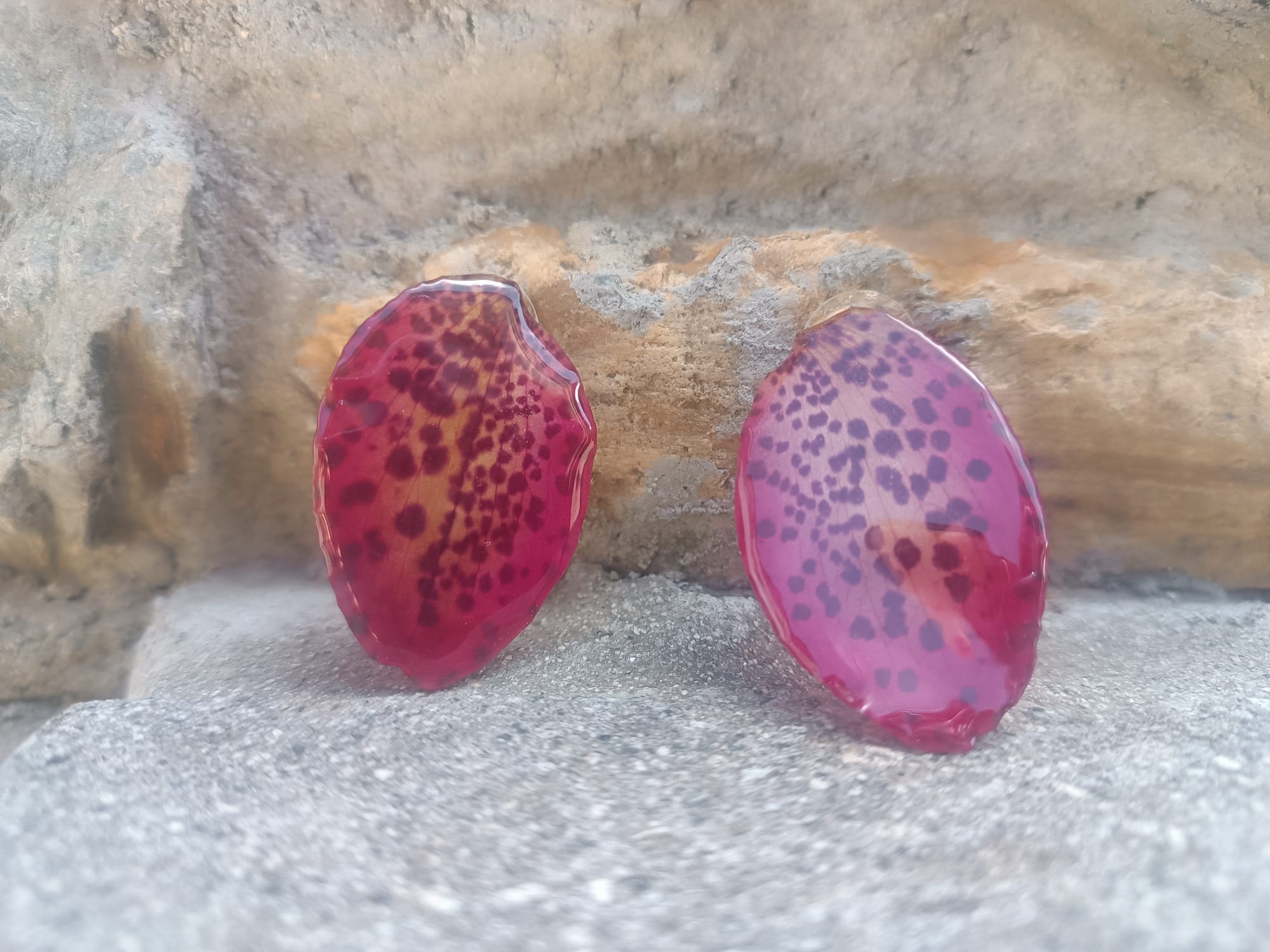Orecchini a perno con chiusura a farfalla realizzati con petali veri di orchidea rosso amaranto dalla trama maculata, esposti sopra la loro scatola regalo bianca con logo Rachele Falvo.