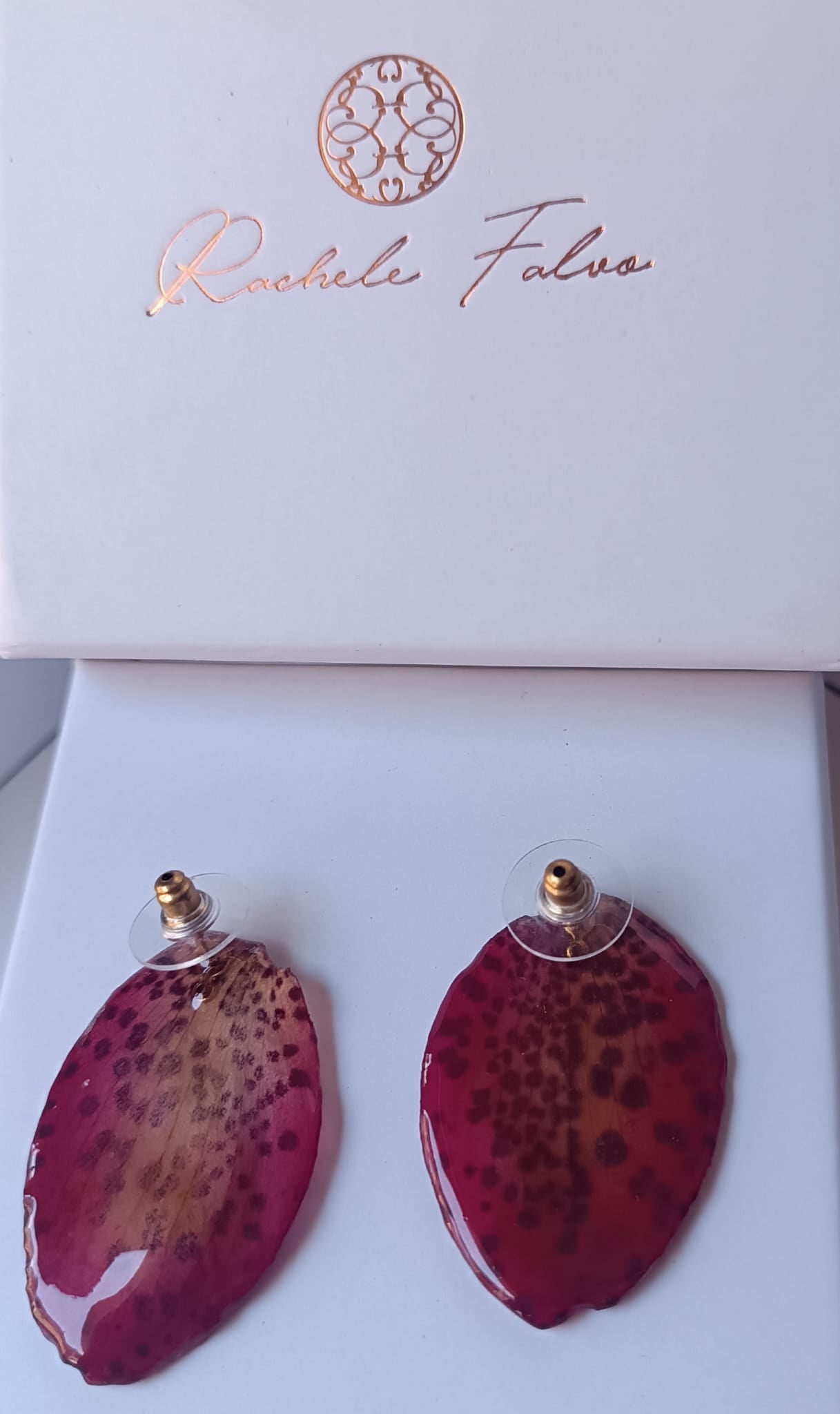 Orecchini a perno con chiusura a farfalla realizzati con petali veri di orchidea rosso amaranto dalla trama maculata, esposti sopra la loro scatola regalo bianca con logo Rachele Falvo.